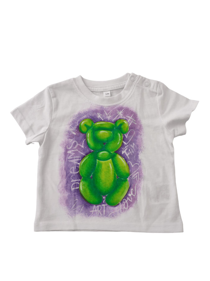 Camiseta blanca con osito verde sobre fondo morado