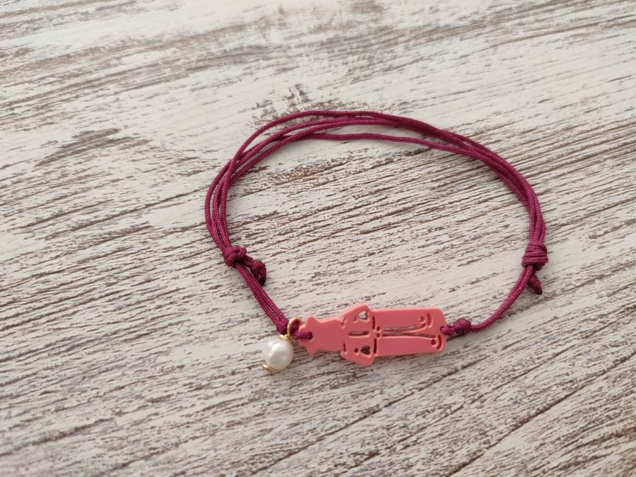 Pulsera de San Roque en color coral con una perla colgando
