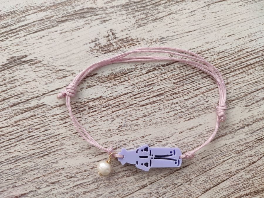 Pulsera en morado claro o lila con cordón rosa y una perla